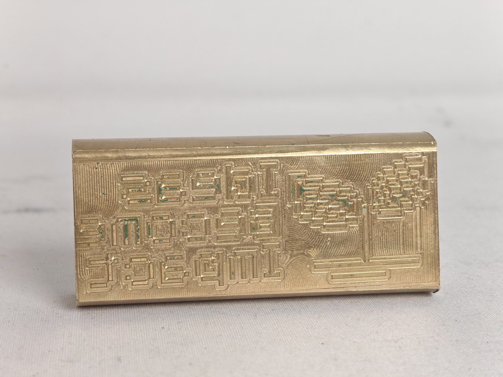 The finished Ideas Become Impact die, pixel lettering milled into the flat top of a round brass bar