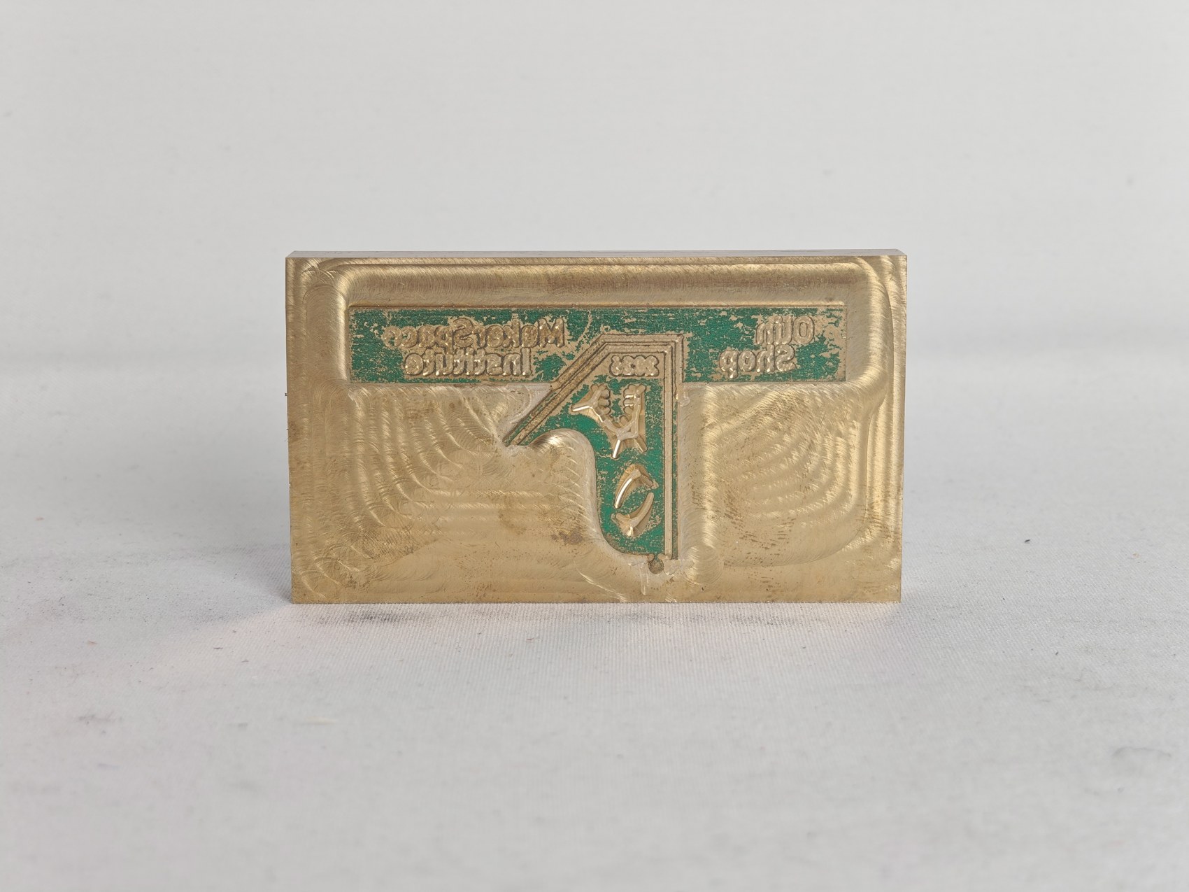 The finished brass die, its lettering mirrored, green foil still in the recesses
