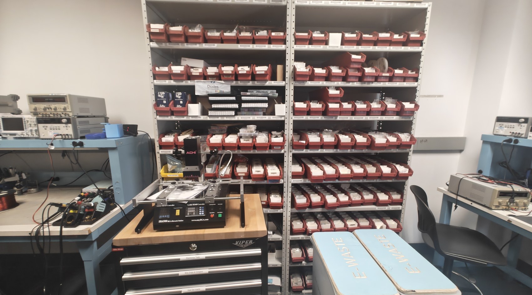 Room 303 before the rebuild: shelves of red component bins crammed against benches, a tool chest and bins on the floor